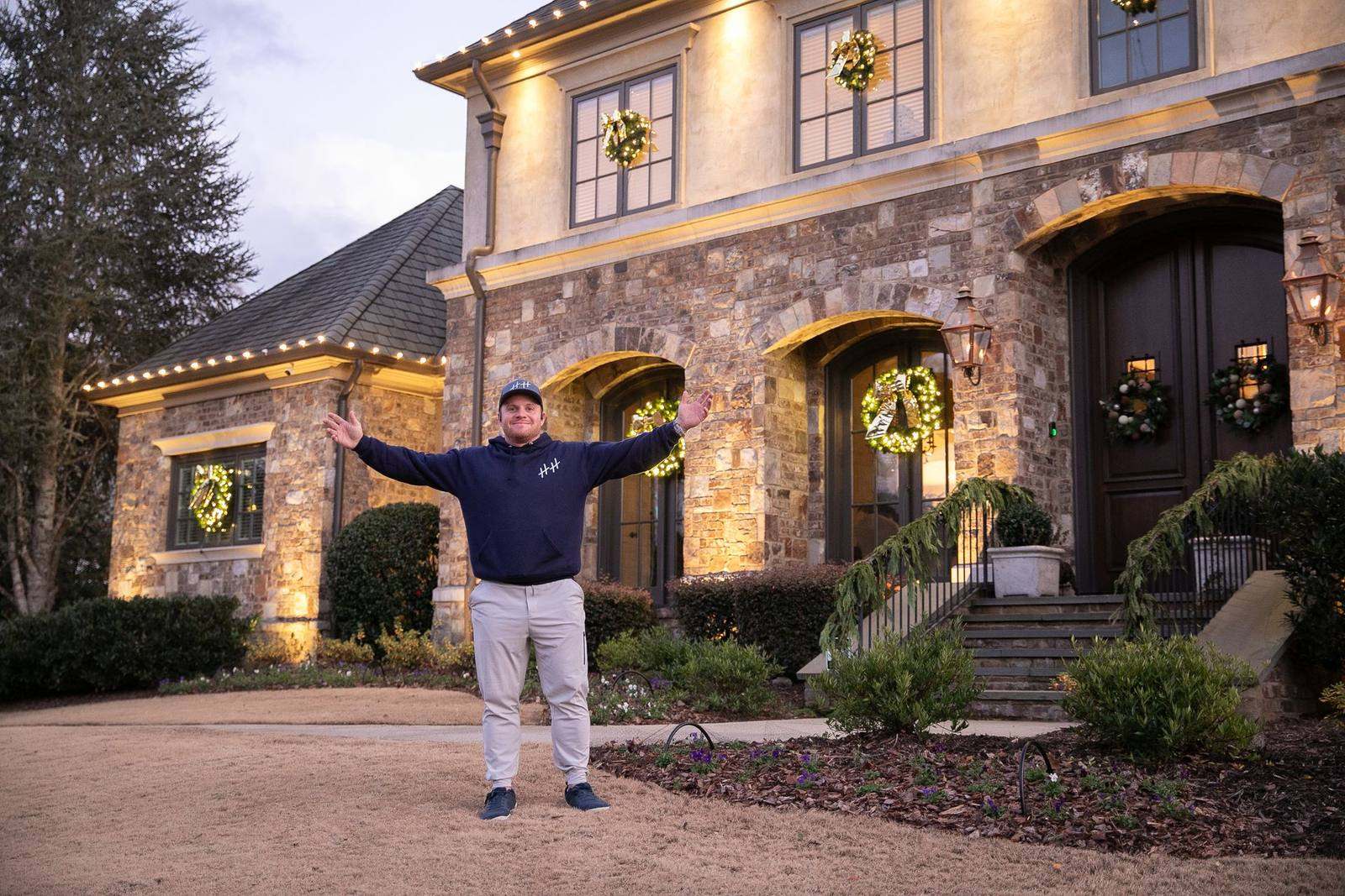 Jordan Utley of Holiday House in front of a lit stone estate at dusk